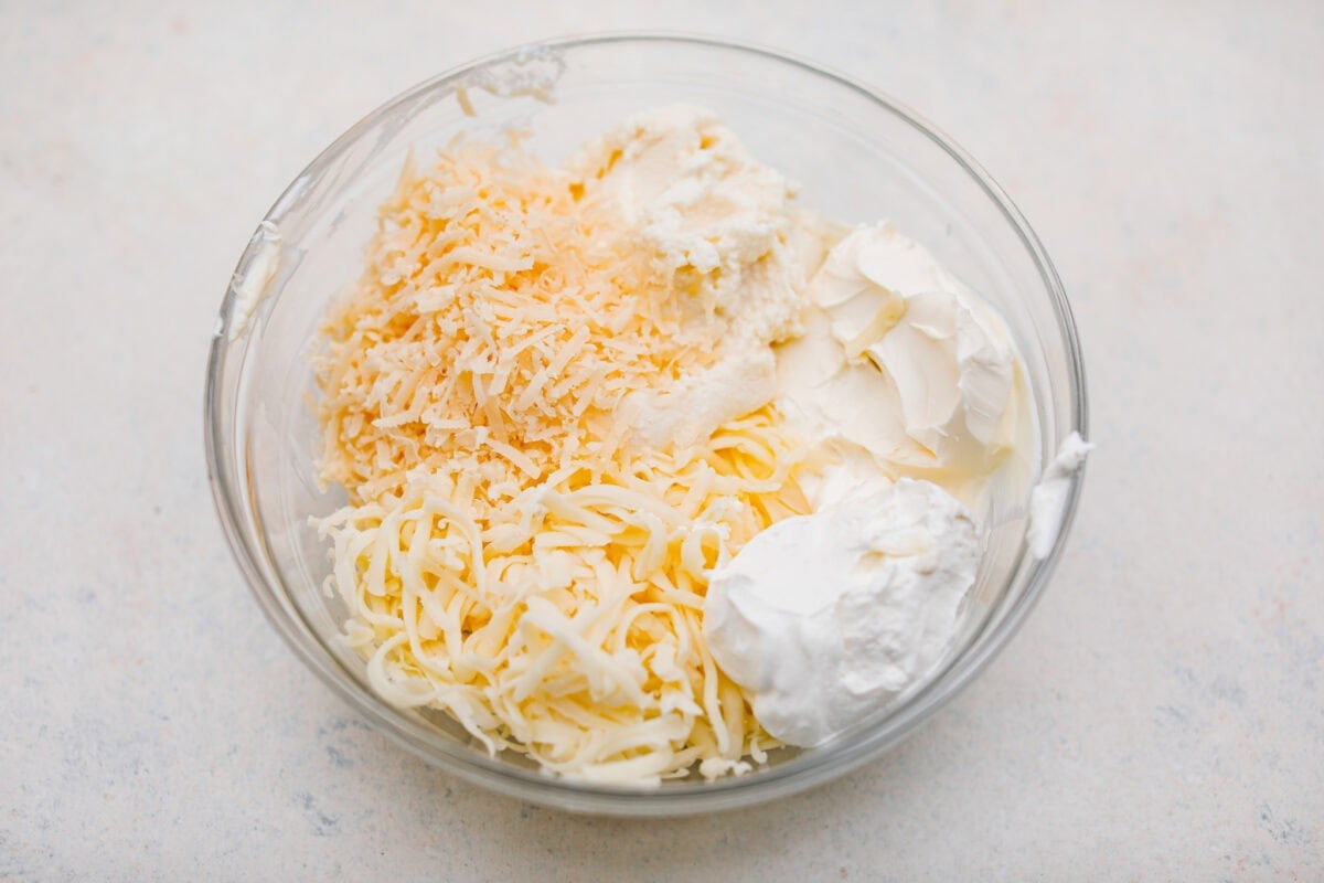 Million Dollar Spaghetti takes baked spaghetti to a whole new level. That cheesy, cream cheese, sour cream, and ricotta layer makes it so dreamy! One bite and you’ll ask, “Wait... why have I not been making spaghetti like this my whole life?” Million dollar spaghetti cheese layer ingredients added to a bowl.