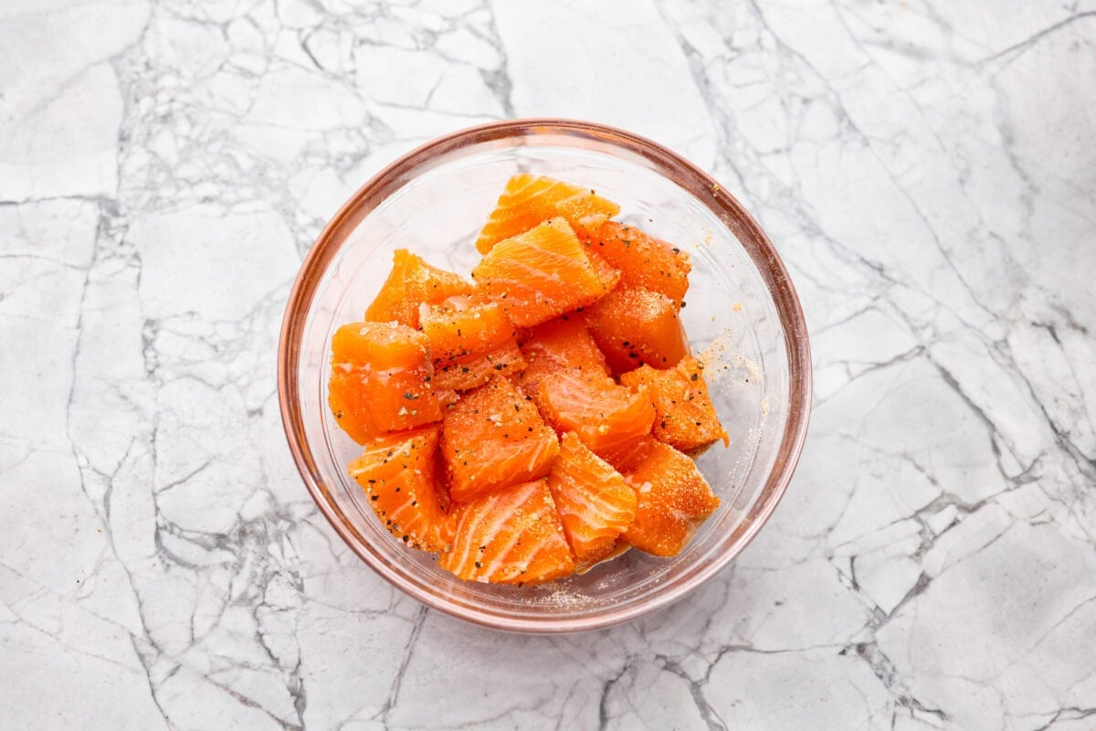 My air fryer salmon rice bowl combines crisp salmon, fluffy rice, fresh veggies, and a spicy sriracha mayo drizzle. Plus, it's ready in less than 20 minutes! Seasoned salmon pieces in a bowl.