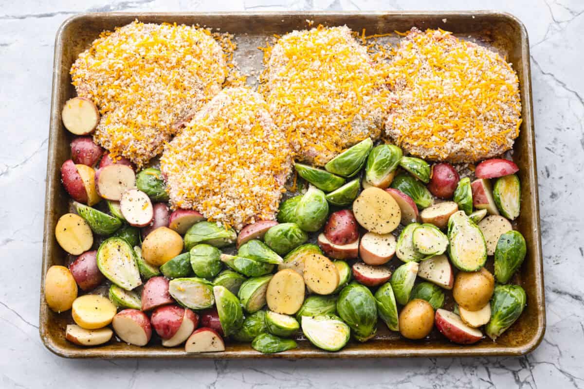 If you're looking for a tasty spin on pork chops, this is it! The crispy, cheesy texture -ย don't even get me started! YUM! Add in some roasted veggies, and you have the best Sheet Pan Crispy Pork Chops dinner! Breaded pork chops and seasoned vegetables on a sheet pan.