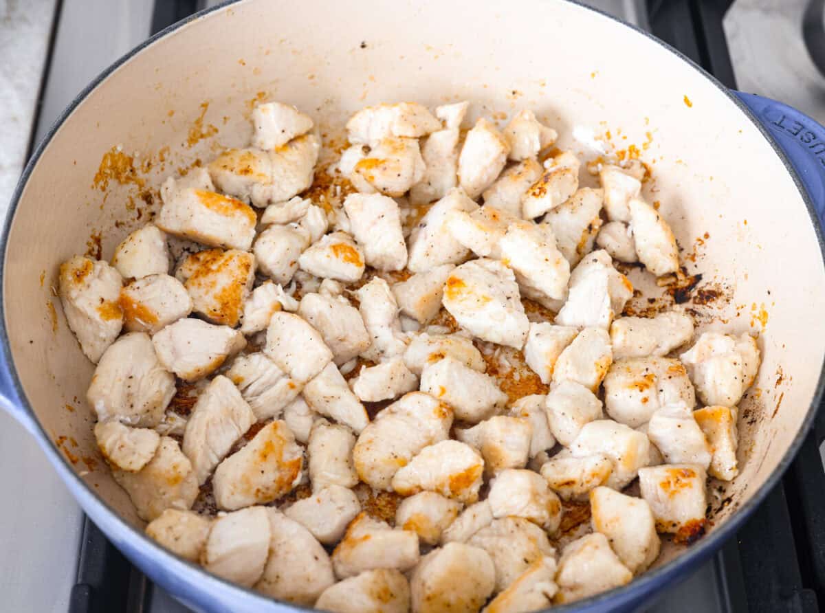Skillet Sesame Chicken & Broccoli is your new favorite weeknight winner! With sweet and savory flavors in every bite, this easy stir-fry comes together in just 30 minutes. Chicken pieces cooking in a skillet on the stove.