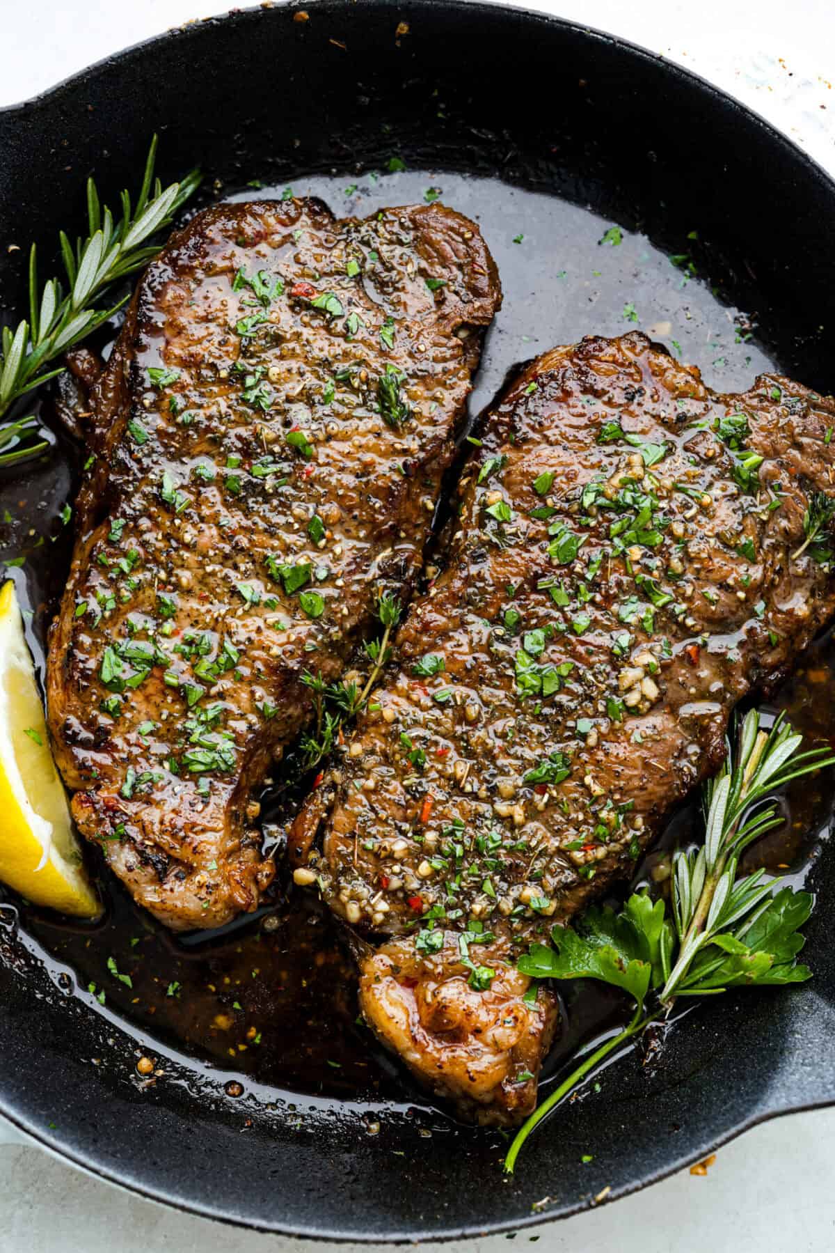 This steak marinade is one of the top recipes on my site! Itโs my go-to for turning tough, budget-friendly cuts into juicy, flavor-packed steaks that practically melt in your mouth. Two Steaks in a skillet with steak marinade.