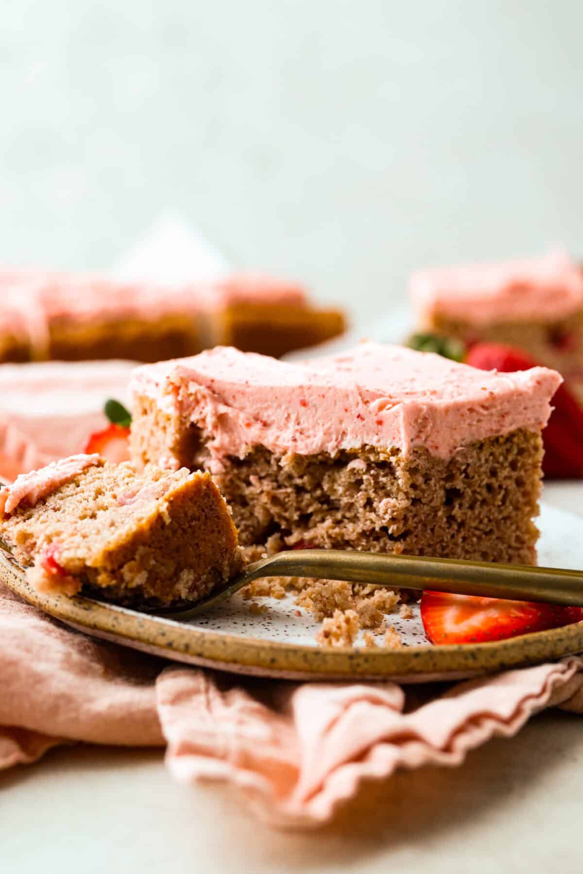 Ever since I discovered the amazing flavors that freeze-dried strawberries add, I’ve been using them as much as possible. This strawberry cake? No exception. And don’t even get me started on the frosting... It’s dangerously good. Slice of strawberry cake on a plate with a fork with a bite of cake on it.