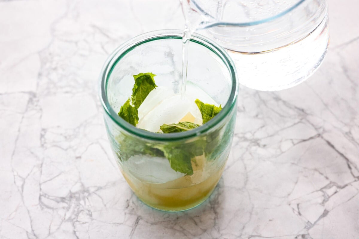 My Virgin Mojito is like a vacation in a glass. Crisp, minty, and packed with fresh lime flavor. This non-alcoholic drink is something my whole family loves! Someone pouring sparkling drink into the mojito mixture.