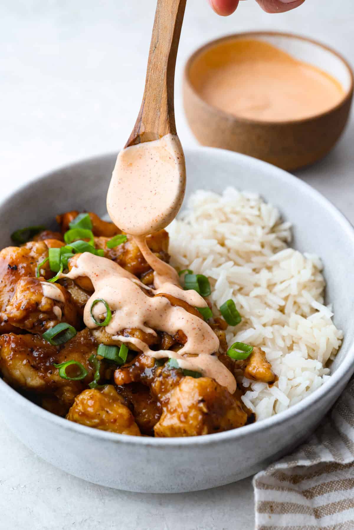 Why You Need Yum Yum Sauce In Your Life! Someone drizzling yum yum sauce over cashew chicken and rice.