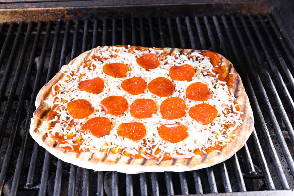 Iโm all about pizza and grilling, so when I can combine the two, itโs a win. The grill gives pizza that smoky, crispy flavor you canโt get from the oven. Trust me, this grilled pizza will have you hooked! Topped pizza on top of the grill, raw side down.