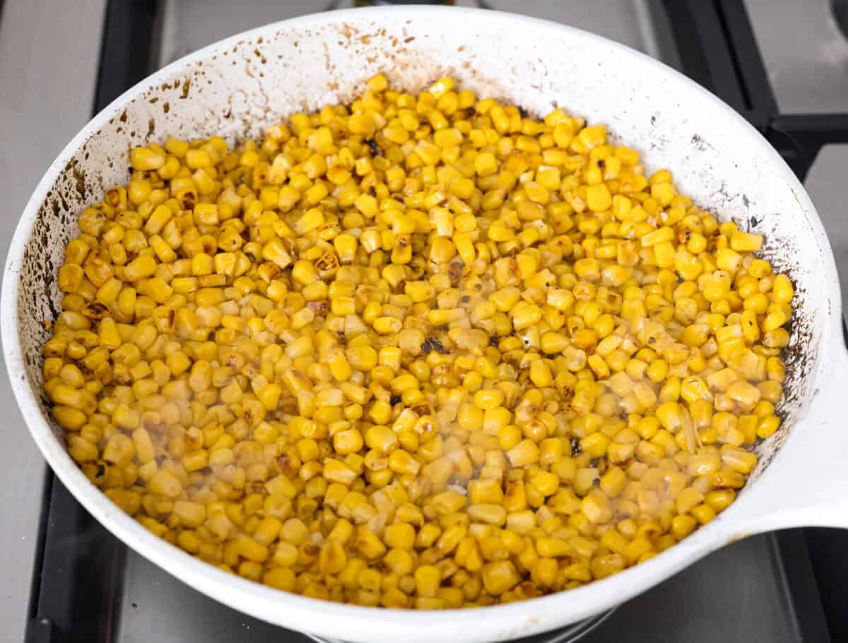 Guys, Iโm obsessed with elote, so obviously I had to turn all that smoky, creamy, cheesy, limey magic into a pasta salad big enough to feed a crowd. This oneโs guaranteed to disappear fast! Corn sautรฉing in a skillet.