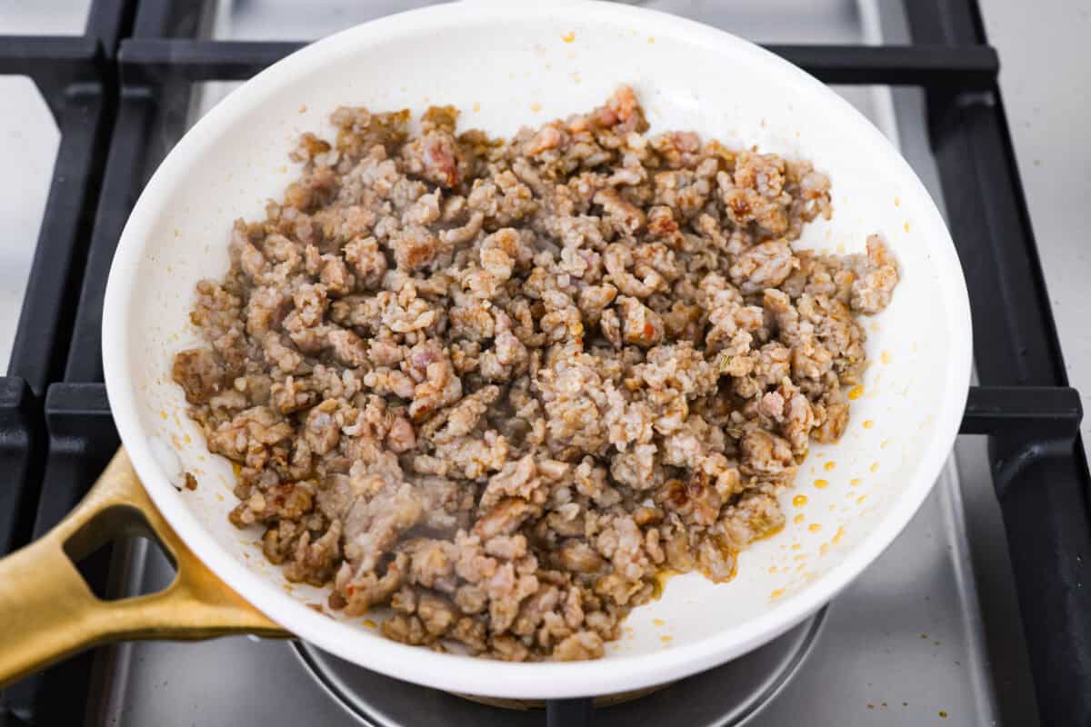 Why make calzones instead of pizza? Sometimes you just want all the pizza vibes without the mess. Calzones are like little pizza presents, warm, cheesy, and you get to make them your way! Sausage cooking in a skillet.