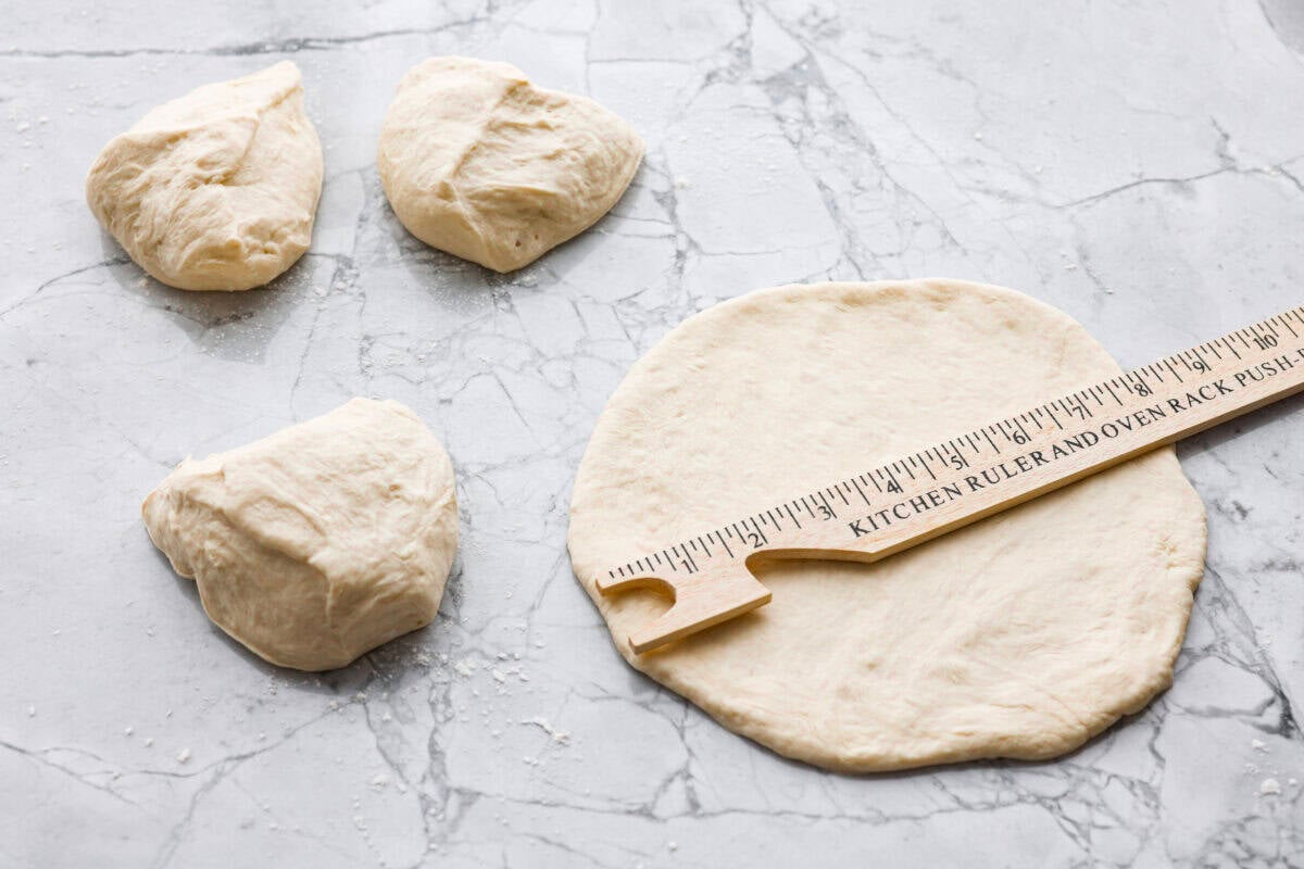 Why make calzones instead of pizza? Sometimes you just want all the pizza vibes without the mess. Calzones are like little pizza presents, warm, cheesy, and you get to make them your way! Pizza dough being separated and shaped into circles.