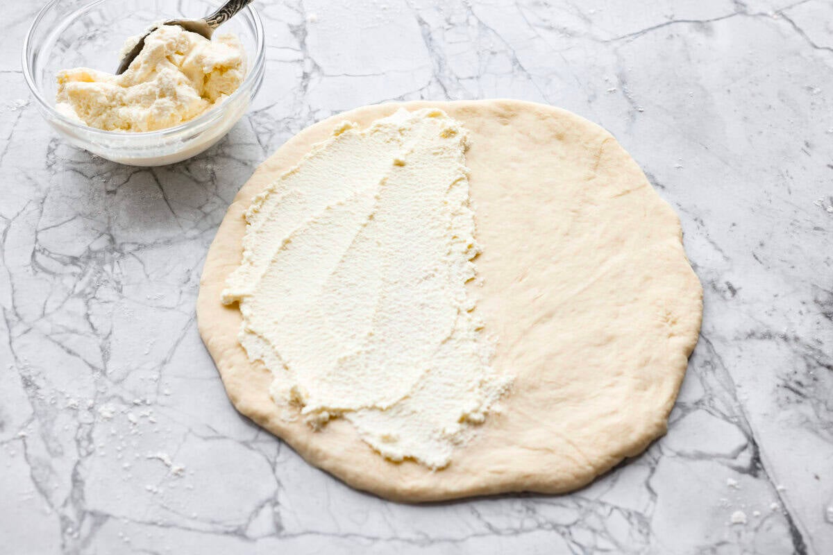 Why make calzones instead of pizza? Sometimes you just want all the pizza vibes without the mess. Calzones are like little pizza presents, warm, cheesy, and you get to make them your way! Ricotta cheese added to one half of the dough circle.