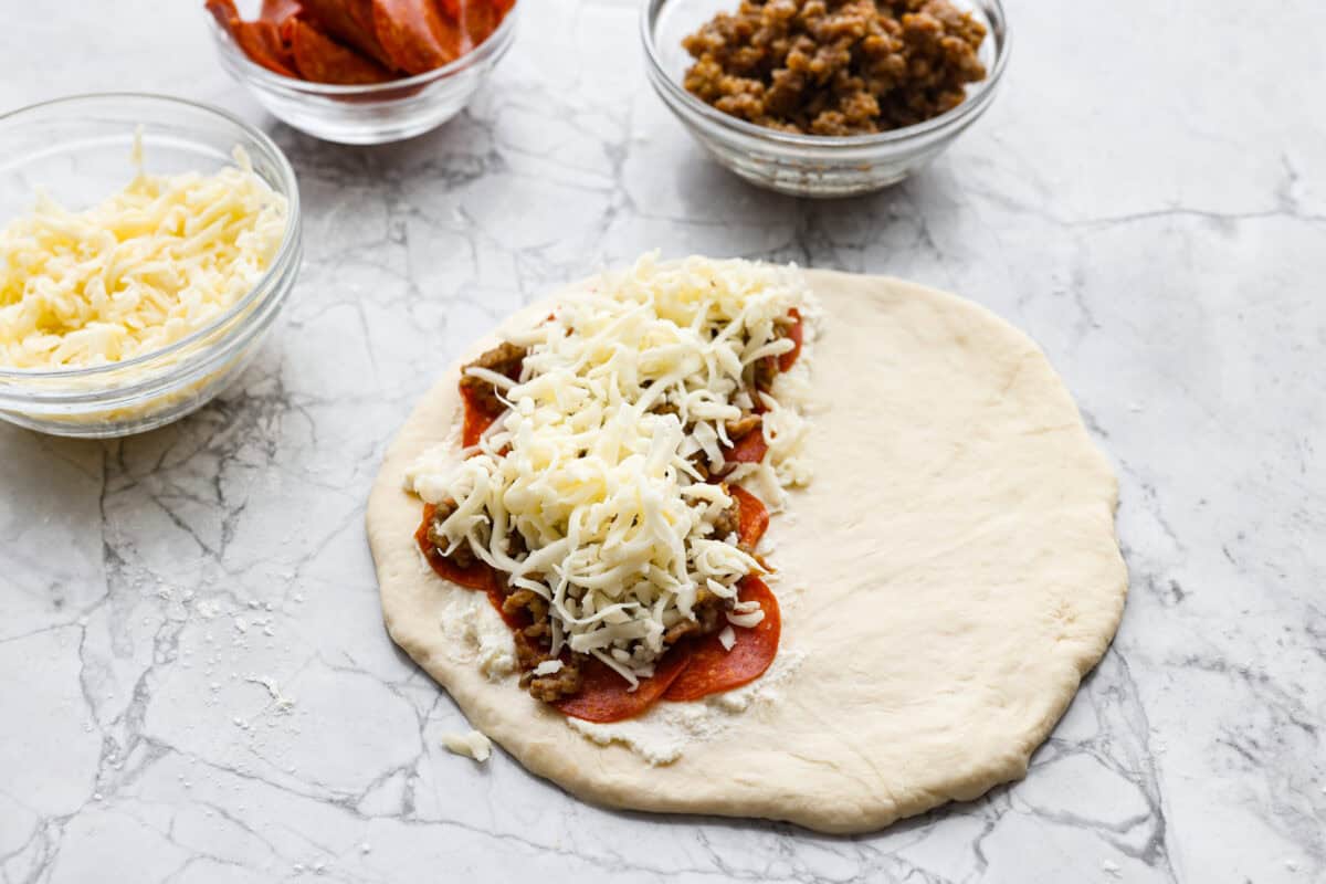 Why make calzones instead of pizza? Sometimes you just want all the pizza vibes without the mess. Calzones are like little pizza presents, warm, cheesy, and you get to make them your way! Pizza toppings added to the top of the ricotta.