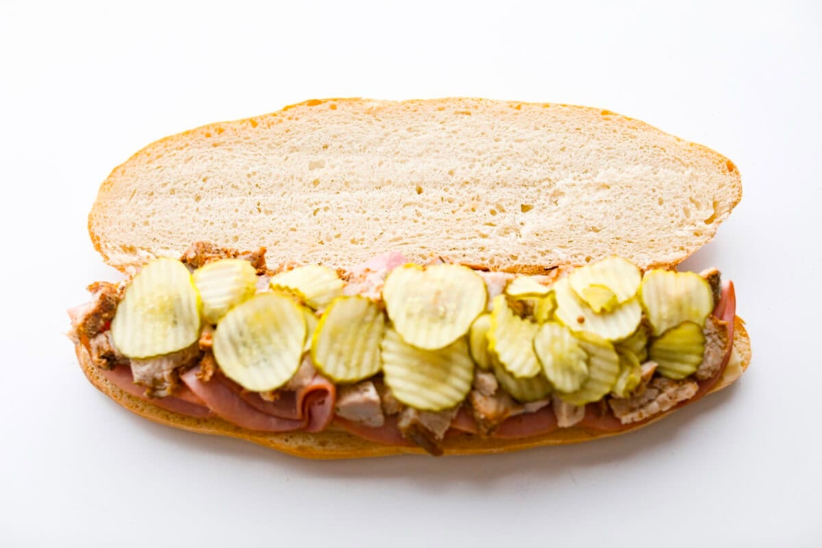 My easy Cuban sandwich is stacked with tender pork, melty Swiss, tangy pickles (my favorite), and zesty mustard! Then it's toasted in butter until perfectly crisp and golden. Ham, pork and pickles added to the top of the cheese on the bread.