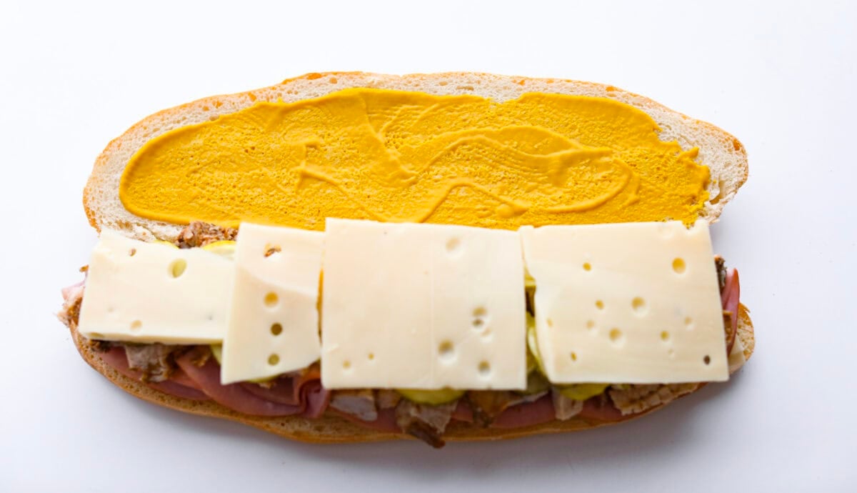 My easy Cuban sandwich is stacked with tender pork, melty Swiss, tangy pickles (my favorite), and zesty mustard! Then it's toasted in butter until perfectly crisp and golden. More cheese added to the top of the pickles and mustard spread on the other half of the bread.