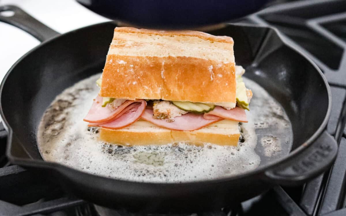 My easy Cuban sandwich is stacked with tender pork, melty Swiss, tangy pickles (my favorite), and zesty mustard! Then it's toasted in butter until perfectly crisp and golden. Prepared sandwich in melted butter in a skillet.