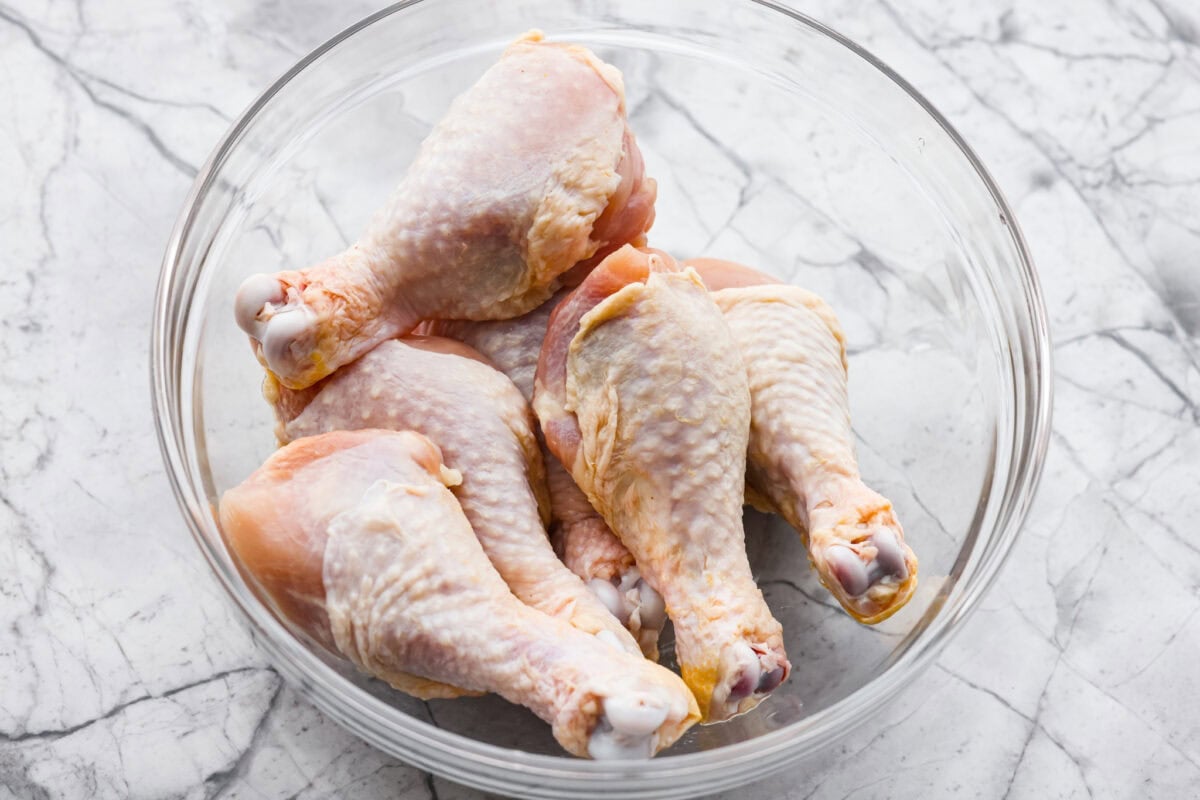 My kids always fight over who gets the chicken legs. With this Air Fryer Chicken Legs recipe, I can whip up a few batches and keep everyone happy! The bold flavor and crispy air-fried skin are totally unbeatable. Raw chicken legs in a bowl.