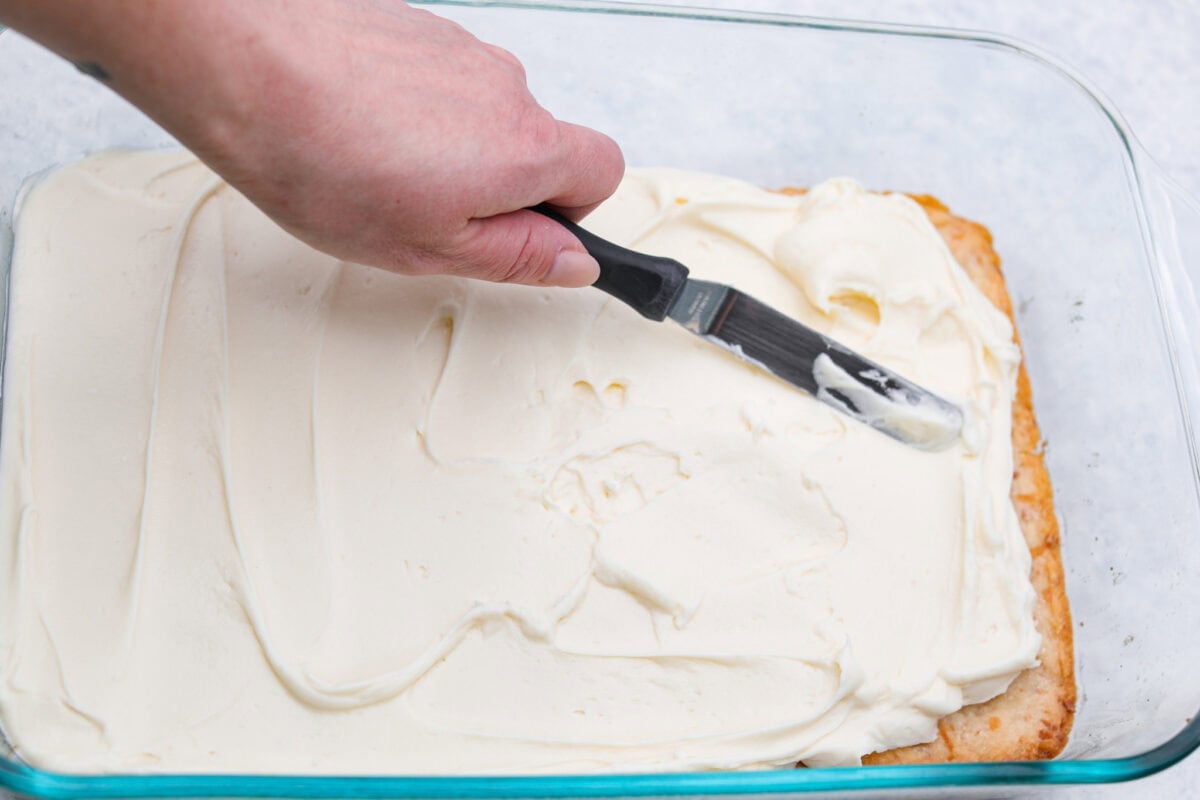 My Dad LOVES coconut cream pie! When I don't have it in me to make a pie, I make this easy Coconut Lush dessert! Itโs rich, dreamy, and always the first dessert to disappear at family gatherings. Someone spreading the cream cheese mixture on top of he crust.