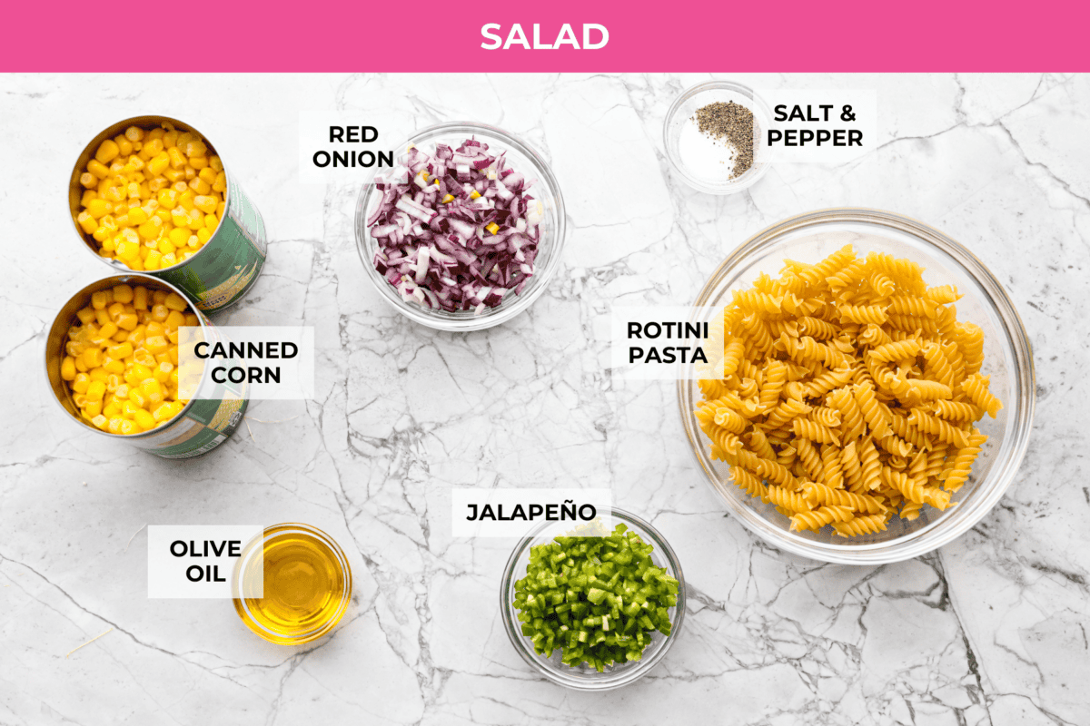 Guys, Iโm obsessed with elote, so obviously I had to turn all that smoky, creamy, cheesy, limey magic into a pasta salad big enough to feed a crowd. This oneโs guaranteed to disappear fast! Overhead shot of labeled salad ingredients.