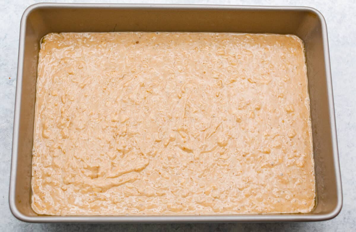 You have to make this oatmeal cake. Itโs an old-school recipe that doesnโt look like much, but that buttery pecan and coconut topping? Itโs gooey, crunchy, and totally addictive! Oatmeal cake batter in the bottom of the pan.