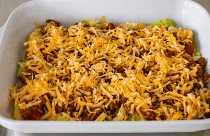 You love my cabbage rolls, and I know you guys love a casserole. So obviously, this cabbage roll casserole is the perfect match. All the delicious flavor with less work! Cheese on top of the meat mixture in the baking dish.