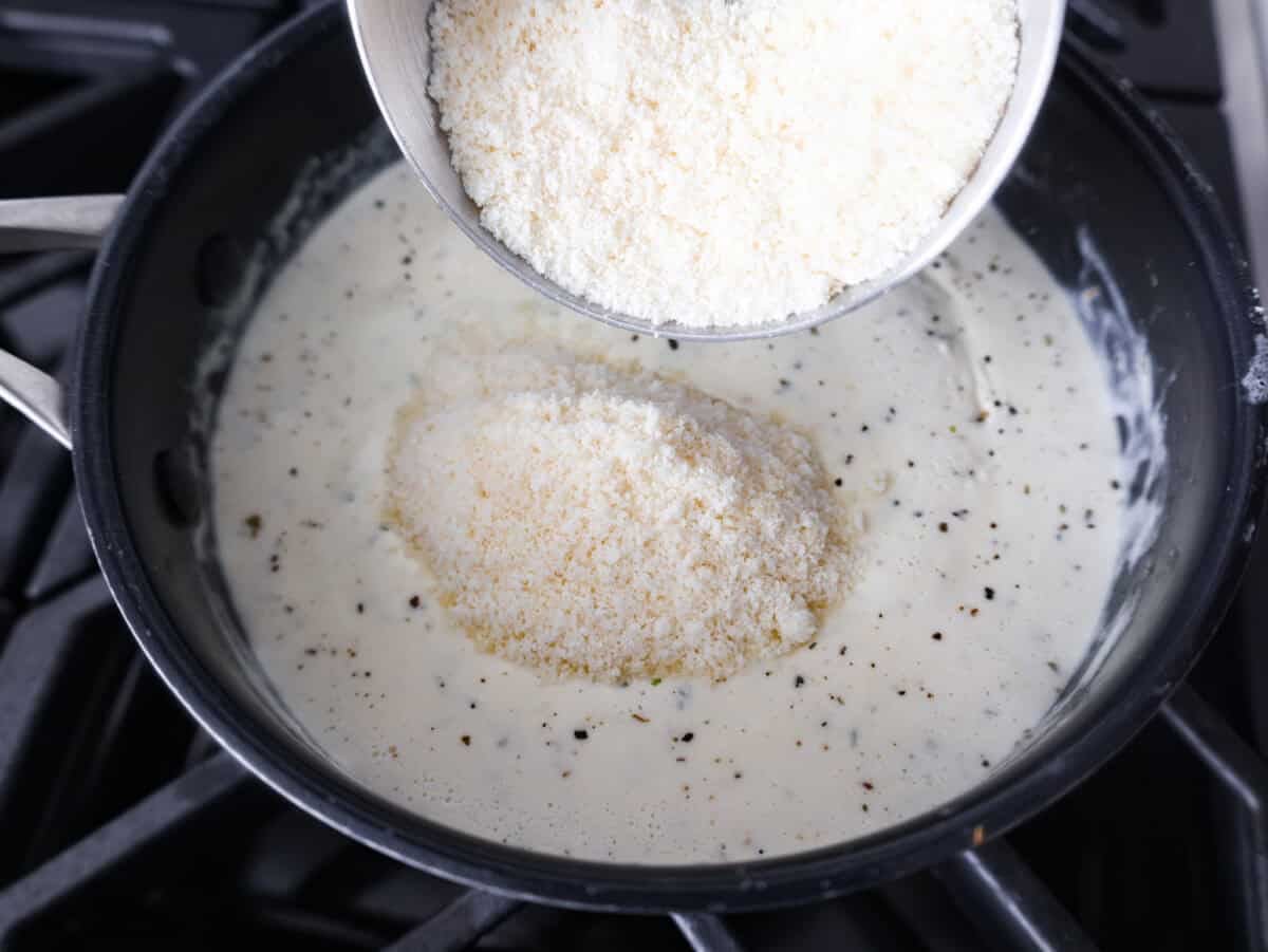 Alfredo sauce is one of my most popular recipes EVER! The secret is a little cream cheese, and ohhh my gosh, the tangy creaminess takes it to the next level. You and your kids will inhale it, I promise! Parmesan cheese being added to the cream and seasoning mixture.