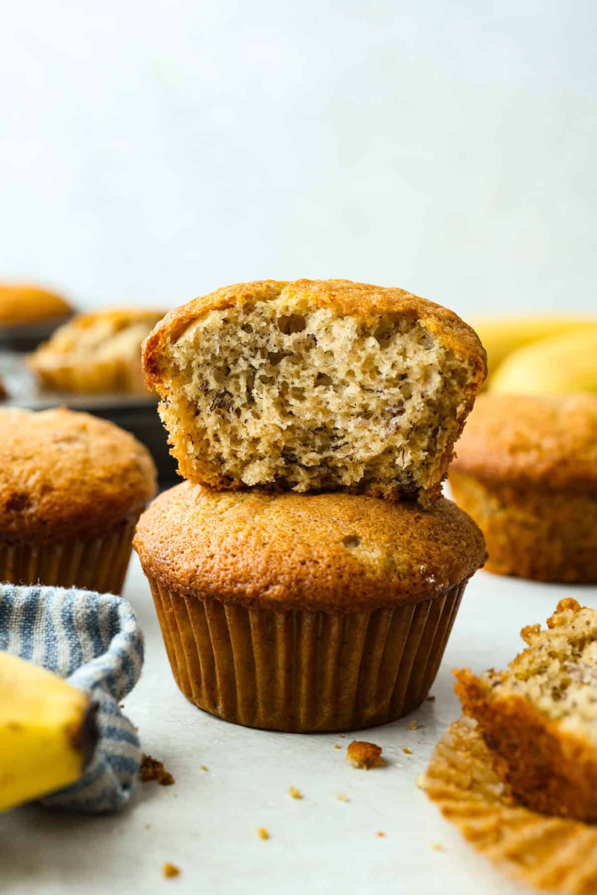 When my bananas start to turn brown and the kids need something quick, these banana muffins always save the day. They’re soft, sweet, and come together fast. Side shot of banana muffins stacked on top of each other. The top one has a bit out of it.