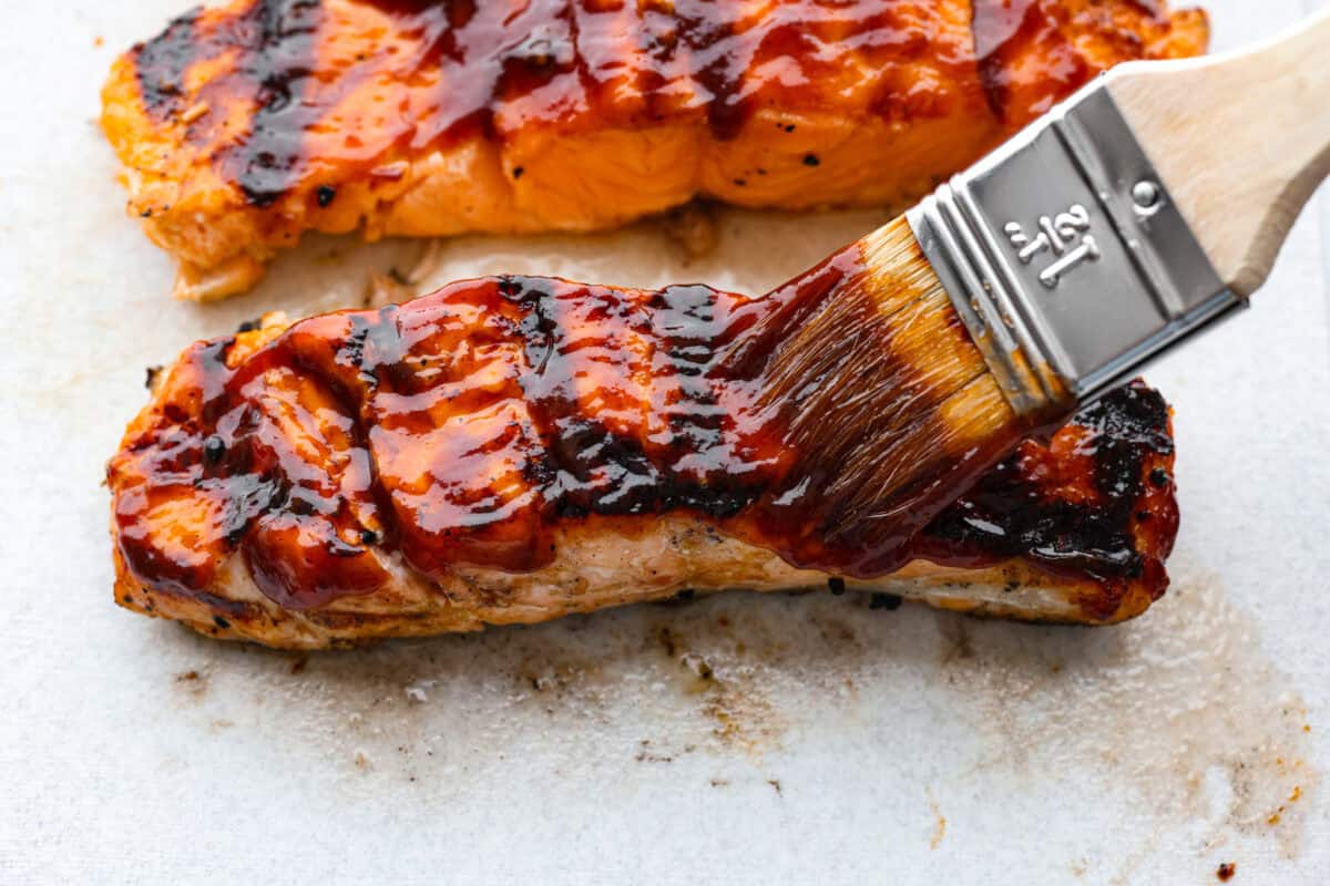 You guys know I'm obsessed with salmon! This BBQ salmon is perfectly smoky, tender, and coated in my mouthwatering homemade barbecue sauce. Saucing up the salmon after its cooked.