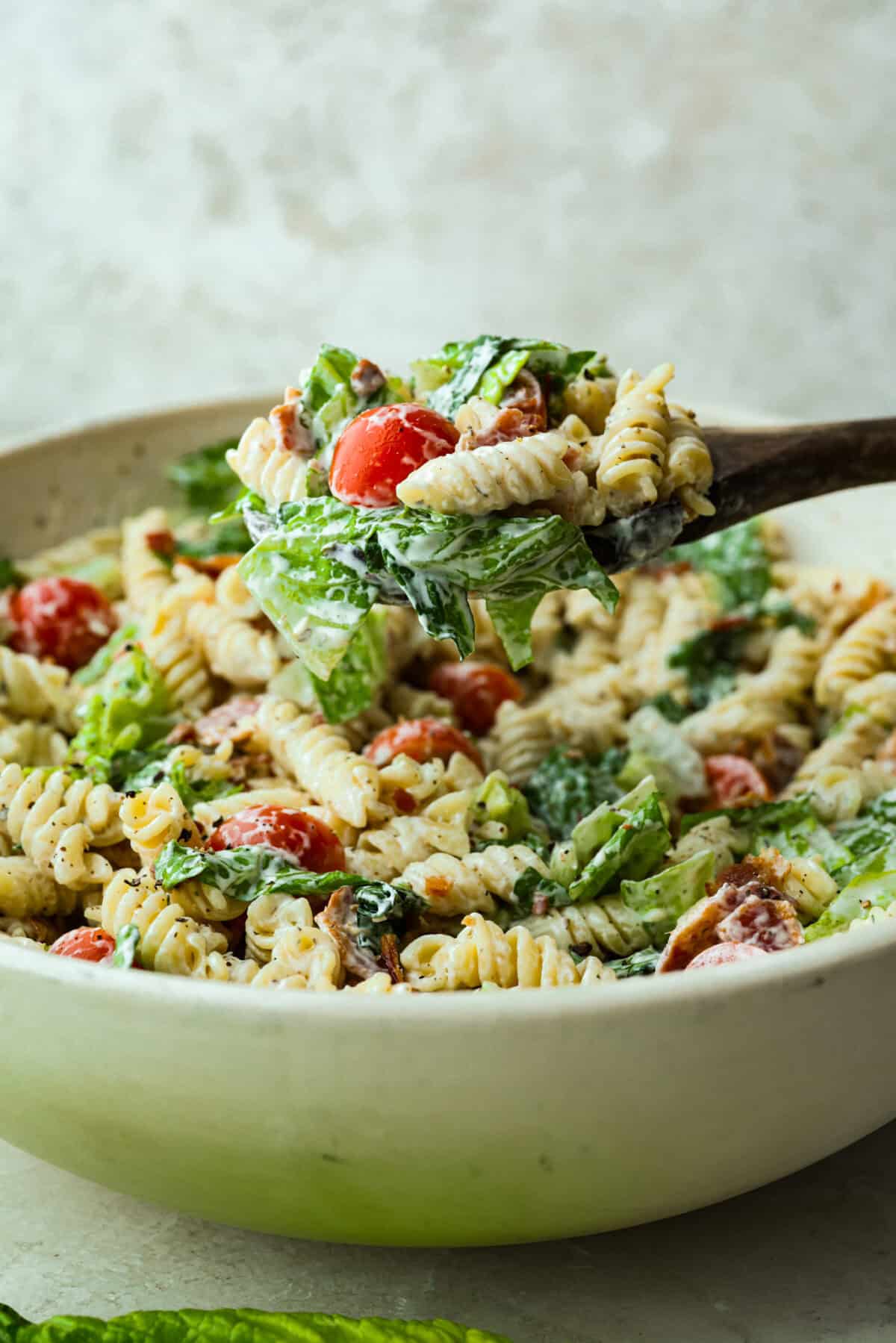 The best sandwich ever? Hands down, a BLT. Add in my obsession with pasta salads and, chefโs kiss! This BLT Pasta Salad has the crispy bacon, juicy tomatoes, and crunchy lettuce we all love! Someone lifting a scoop of BLT pasta salad out of the large pasta bowl.