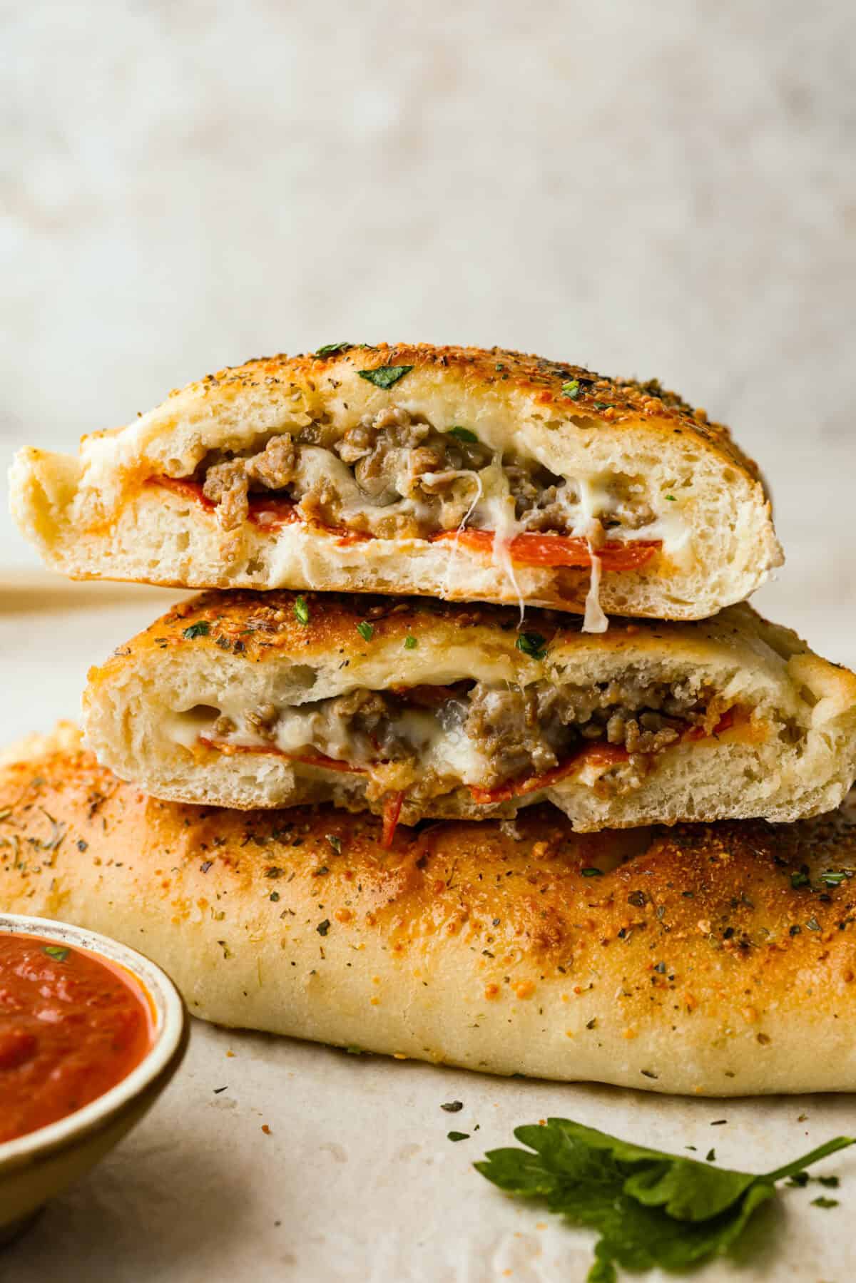 Why make calzones instead of pizza? Sometimes you just want all the pizza vibes without the mess. Calzones are like little pizza presents, warm, cheesy, and you get to make them your way! Stack of calzones, with one cut in half.