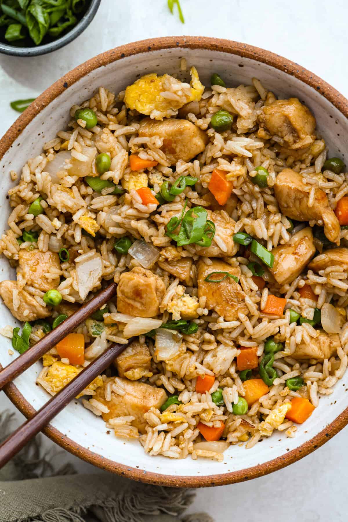 My go-to when I donโt feel like cooking? This easy chicken fried rice. I grab leftover rice and chicken, toss it all in a pan, and boom, dinner is ready in minutes. The best part? My kids devour it! Bowl of chicken fried rice with chopsticks.