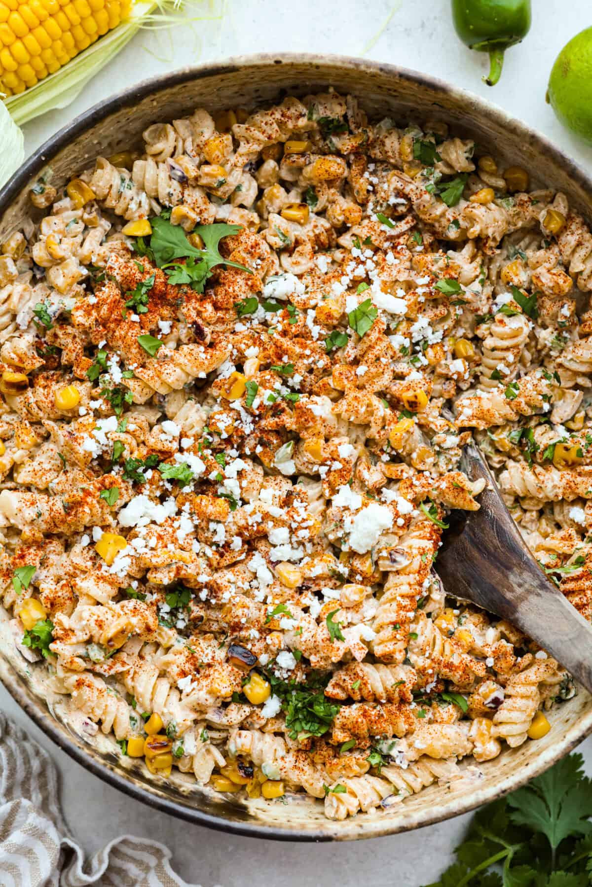 Guys, Iโm obsessed with elote, so obviously I had to turn all that smoky, creamy, cheesy, limey magic into a pasta salad big enough to feed a crowd. This oneโs guaranteed to disappear fast! Overhead shot of elote pasta salad in a serving bowl.