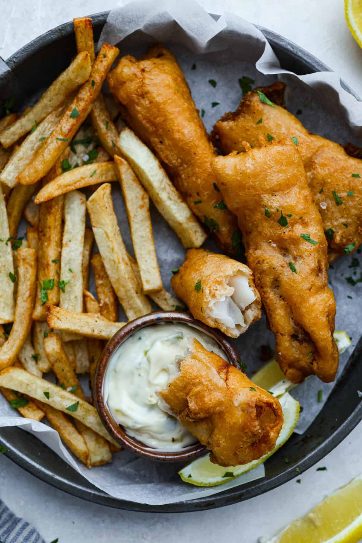 Skip the overpriced takeout and bring the pub vibes home! Crispy, golden fish and chips—light, flaky, pan-fried perfection. It’s cheaper, easier, and honestly? Way better than anything stuffed in a greasy paper bag. Plate of fish and chips with tartar sauce.
