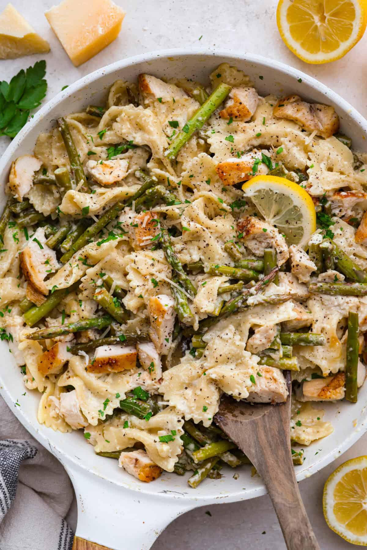 My Lemon Garlic Chicken Asparagus Pasta looks like something youโd order at a fancy bistro, but it literally takes 30 minutes! Itโs zesty, garlicky, and seriously so good! Overhead shot of lemon chicken asparagus pasta in a skillet.