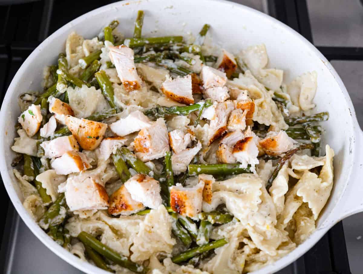 My Lemon Garlic Chicken Asparagus Pasta looks like something youโd order at a fancy bistro, but it literally takes 30 minutes! Itโs zesty, garlicky, and seriously so good! Chicken and pasta added to the skillet.