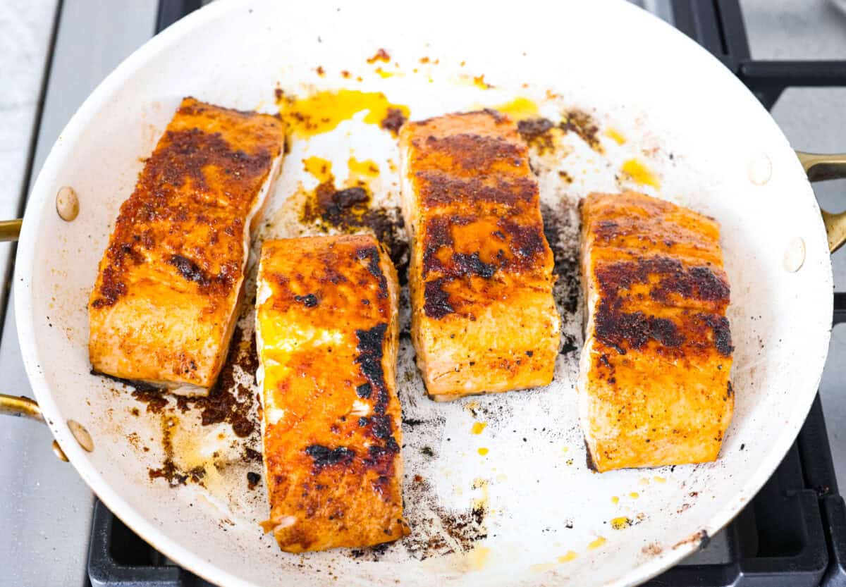Iโm obsessed with salmon, and this Mango Salsa Salmon might just be my new favorite! Itโs super flavorful, fast to cook, and somehow my kids donโt fight me on it. That bright, juicy salsa on top? Freaking amazing. I could eat it every night! Filets cooking in a pan on a stove top.