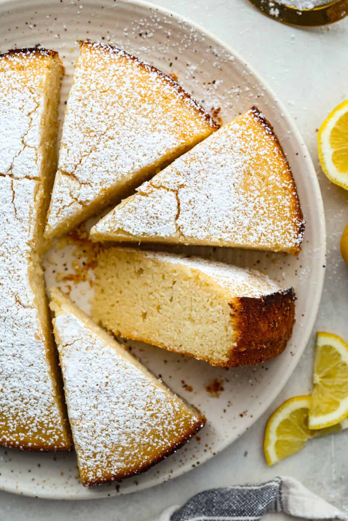 I used to make this with chocolate chips (RIP to that version), but after tasting this zesty lemon ricotta cake upgrade, I’m never looking back. Soft and rich from the ricotta, and that lemon? Chef’s kiss. Cooked lemon ricotta cake on a serving plate dusted with powdered sugar on top.