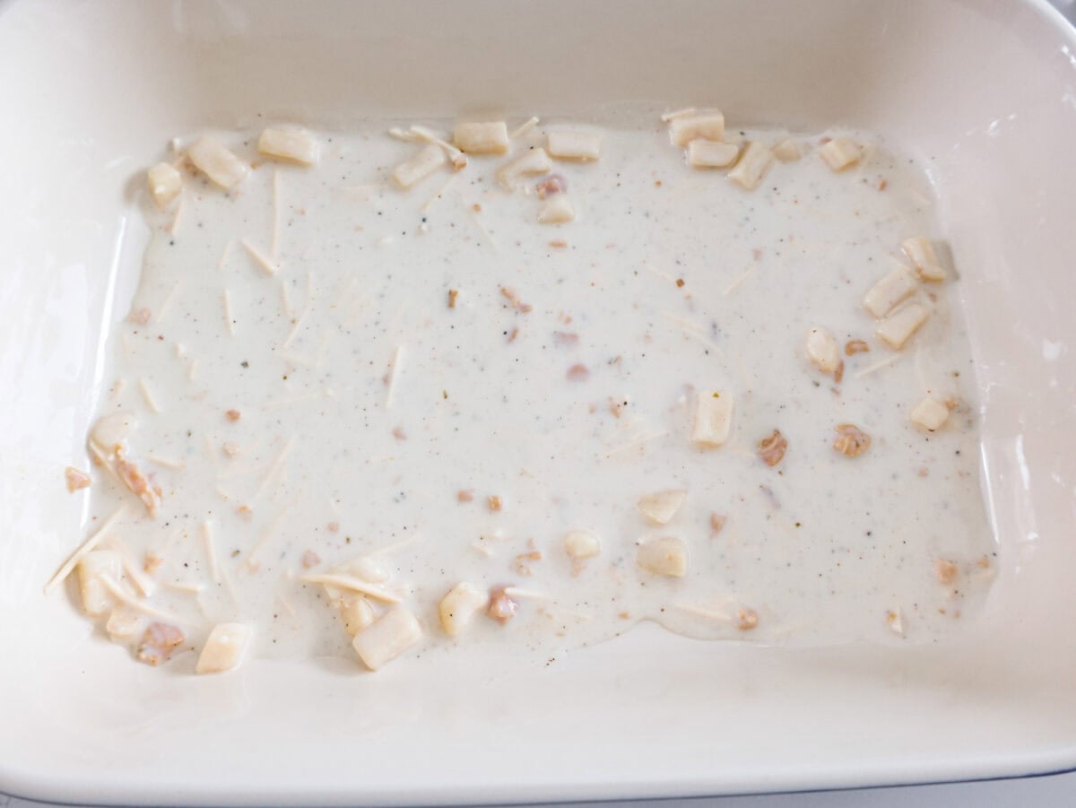 If youโre a seafood lover, you'll be obsessed with this Seafood Lasagna. Iโm talking crab, scallops, and shrimp in creamy, cheesy layers, baked to bubbly perfection. Itโs my go-to dinner when Iโm cooking for seafood fans! Some of the seafood lasagna sauce poured onto the bottom of a baking dish.