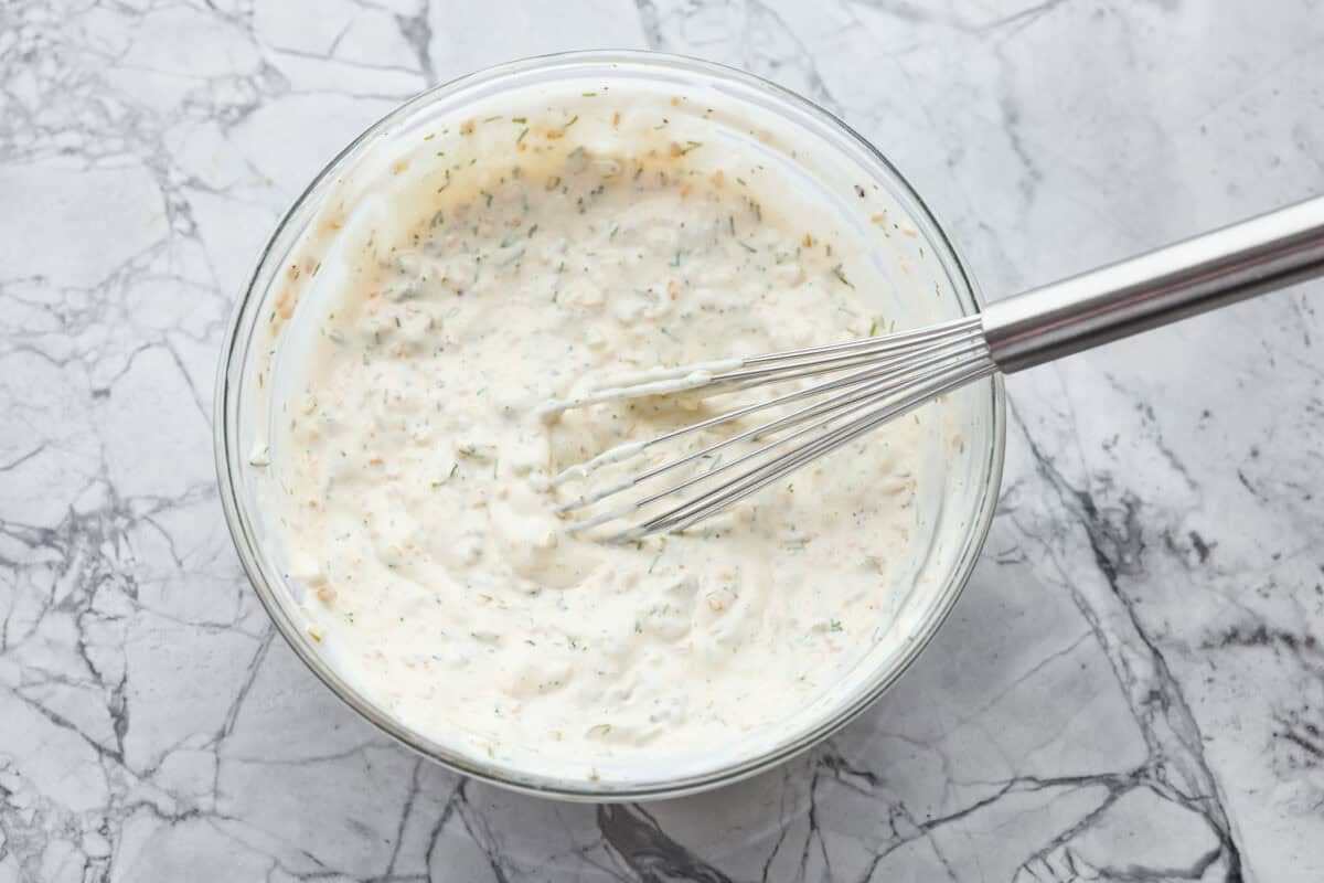 Tartar Sauce uses fresh herbs and my favorite, crunchy dill pickles. My recipe is unique because it uses dried onion, giving it the best punch of flavor and texture! All of the ingredients mixed together in a bowl.