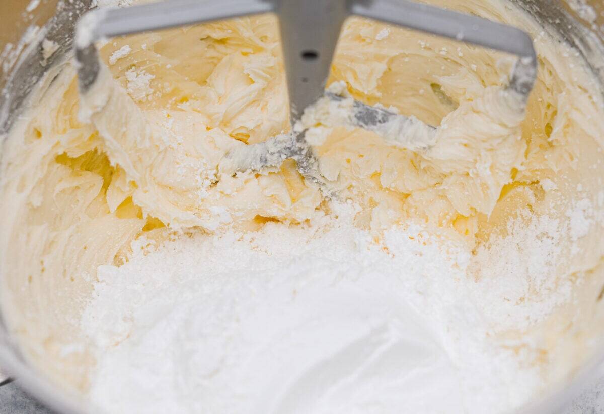 Let me just say, when it comes to frosting, I know what I’m doing. I’ve whipped, piped, and taste-tested my way through more buttercream frosting than I care to admit, and this one? It’s the gold standard. Powdered sugar being added in two stages to the whipped butter.