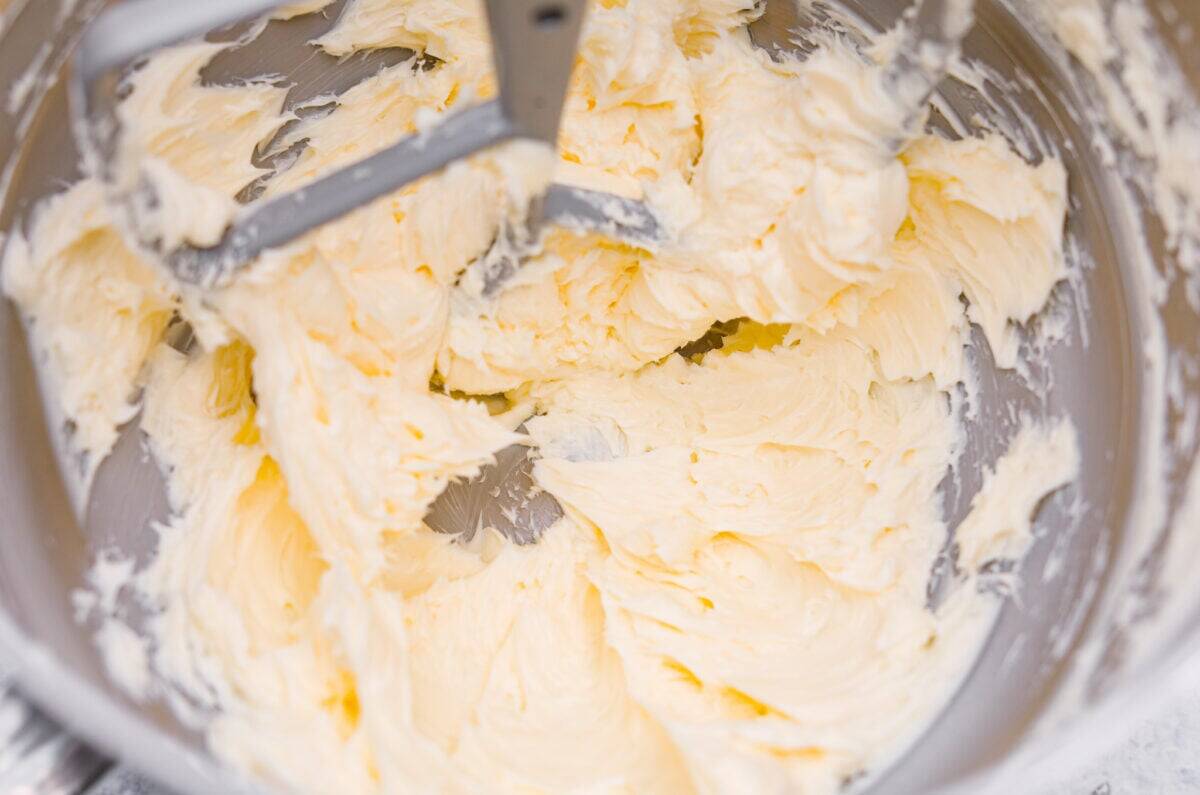 Let me just say, when it comes to frosting, I know what I’m doing. I’ve whipped, piped, and taste-tested my way through more buttercream frosting than I care to admit, and this one? It’s the gold standard. Overhead shot of butter being whipped in a stand mixer.