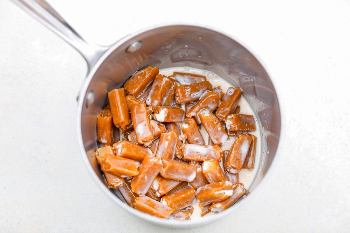 Caramel brownies just got easier! Made with cake mix and melted caramel candies, they’re rich, gooey, egg-free, and fuss-free. This will be your new favorite shortcut dessert! Caramels melting in a pot with evaporated milk.