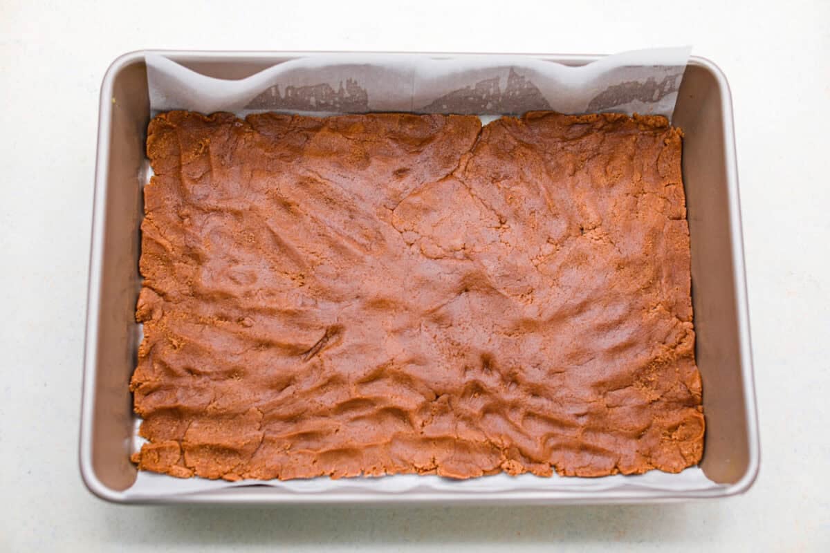 Caramel brownies just got easier! Made with cake mix and melted caramel candies, they’re rich, gooey, egg-free, and fuss-free. This will be your new favorite shortcut dessert! Brownie batter smashed into the bottom of a baking pan.