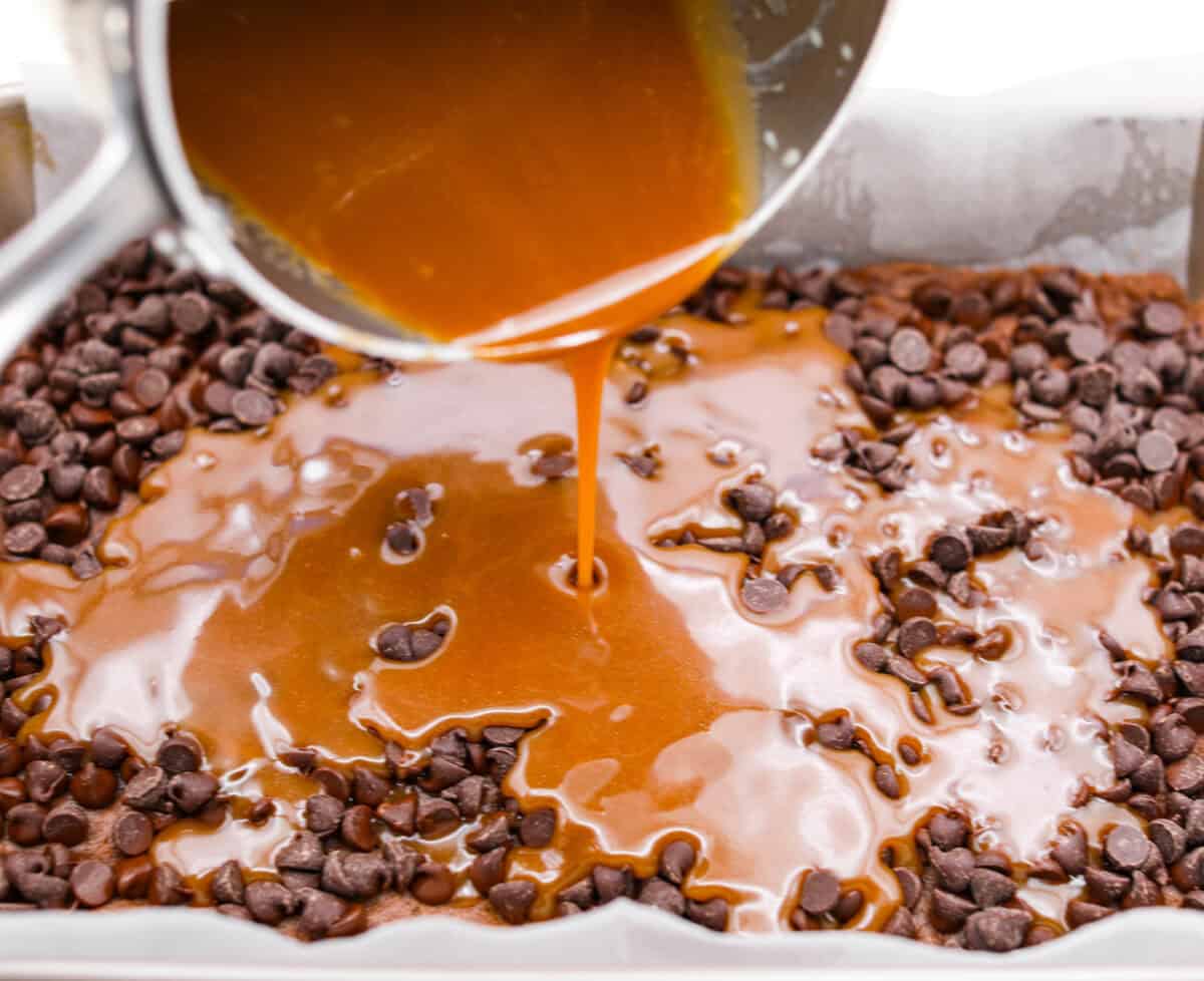 Caramel brownies just got easier! Made with cake mix and melted caramel candies, they’re rich, gooey, egg-free, and fuss-free. This will be your new favorite shortcut dessert! Melted caramel being poured over the chocolate chips.