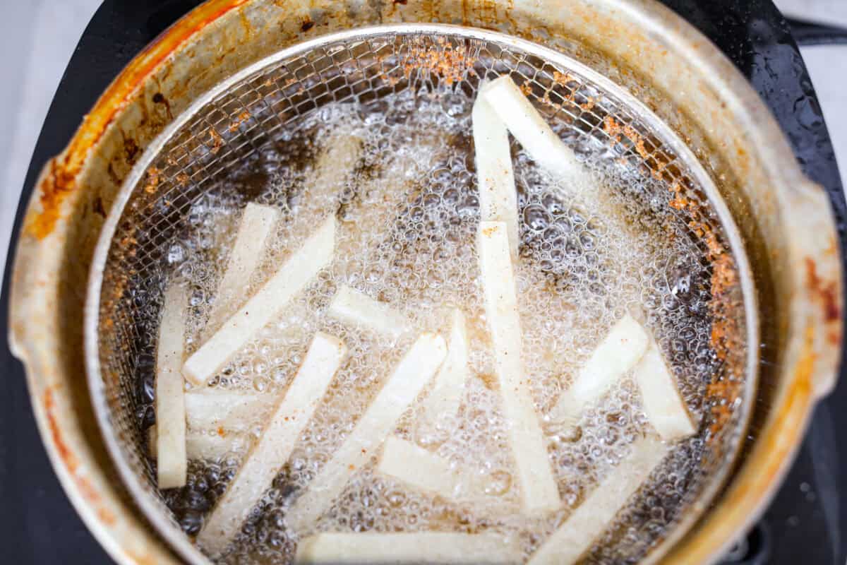 Skip the overpriced takeout and bring the pub vibes home! Crispy, golden fish and chips—light, flaky, pan-fried perfection. It’s cheaper, easier, and honestly? Way better than anything stuffed in a greasy paper bag. Dried off fries deep frying in oil in a frying basket.