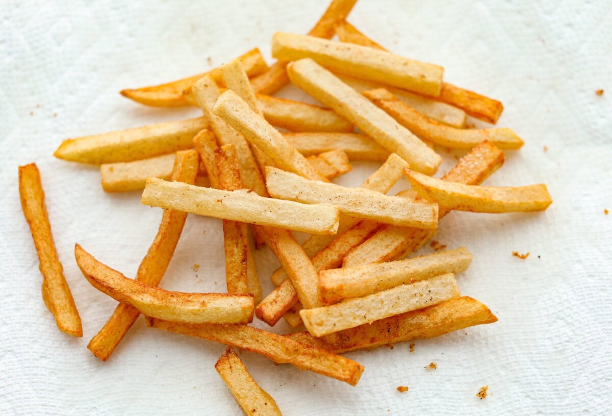 Skip the overpriced takeout and bring the pub vibes home! Crispy, golden fish and chips—light, flaky, pan-fried perfection. It’s cheaper, easier, and honestly? Way better than anything stuffed in a greasy paper bag. Cooked fries on a paper towel seasoned.