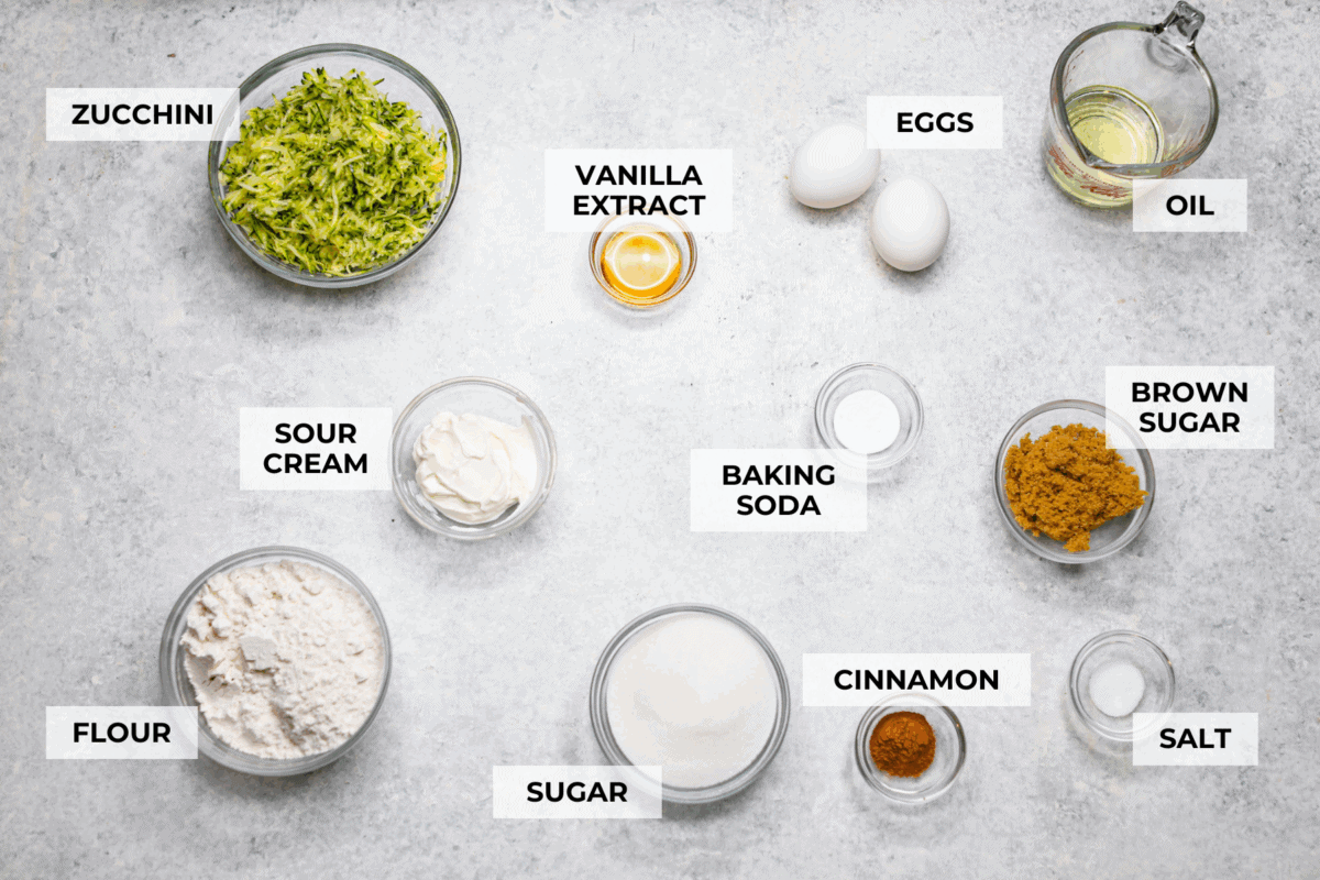 You better believe I count down to zucchini season so I know when I can make this delicious Zucchini Bread! It’s moist, perfectly spiced, and loaded with the best flavor and a hint of veggies! Overhead shot of labeled zucchini bread ingredients.