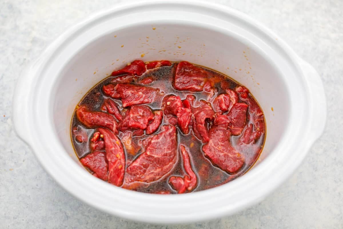 This beef and broccoli takes just minutes to toss in the slow cooker, and itโs hands-down one of my top recipes on the site! The beef turns melt-in-your-mouth tender, and the flavor is totally next level! Beef slices and sauce in a crock pot.