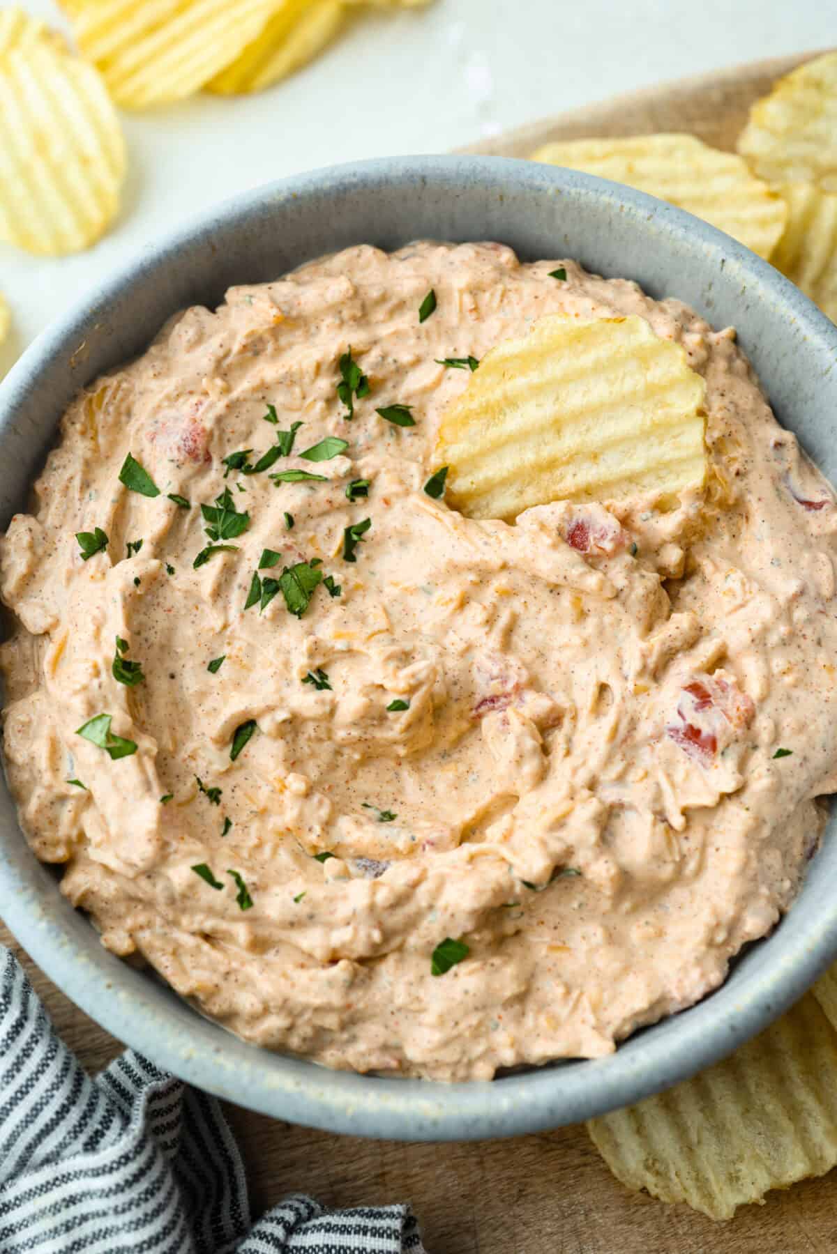 Boat dip in a serving bowl with a potato chip.