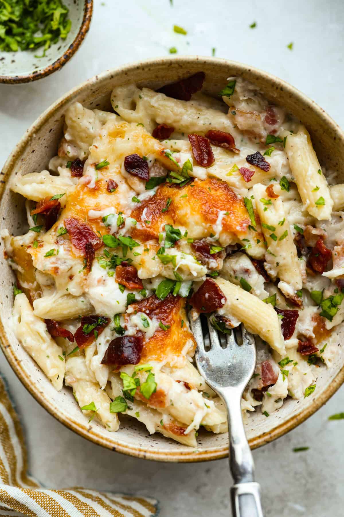 Want to make something you know your kids will eat? This chicken bacon ranch casserole is it! I can't tell you how delicious this casserole is! The combination of flavors is perfection! You have to try it! Bowl of chicken bacon ranch casserole with a fork.