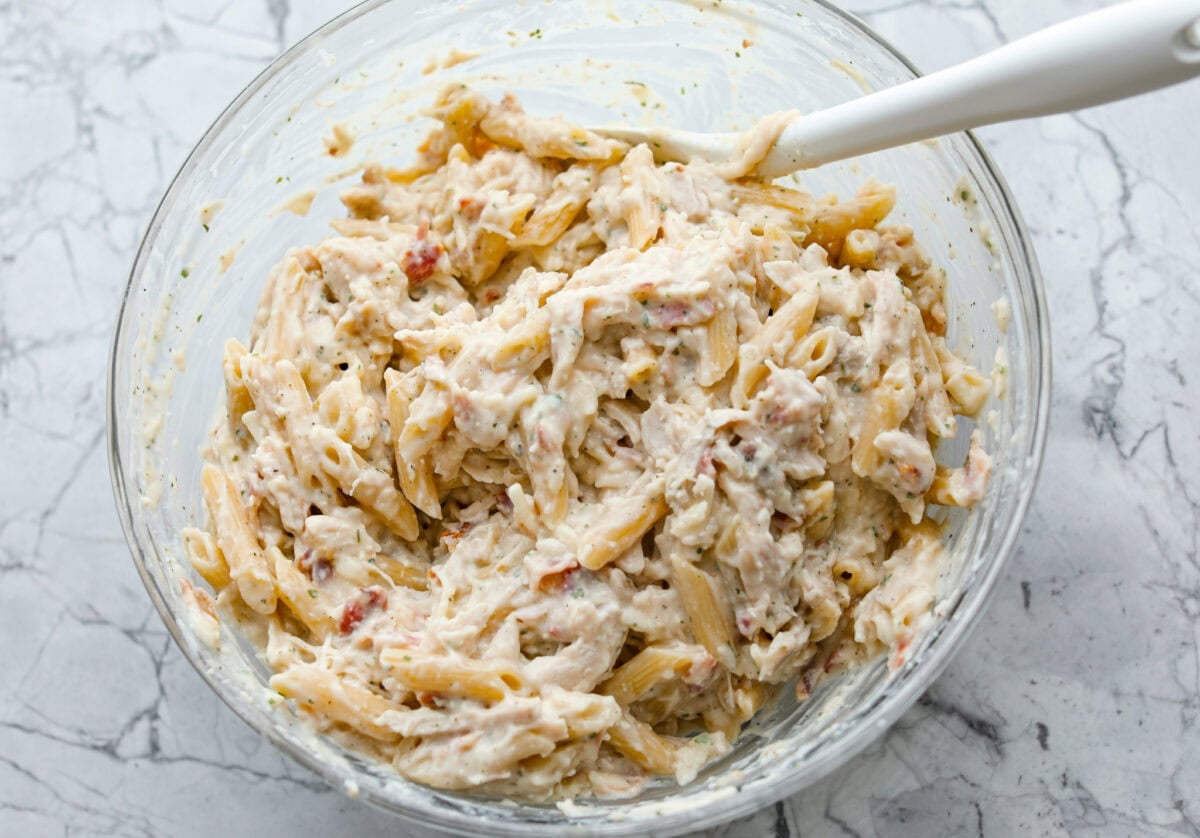 Want to make something you know your kids will eat? This chicken bacon ranch casserole is it! I can't tell you how delicious this casserole is! The combination of flavors is perfection! You have to try it! All of the casserole ingredients, including the cooked pasta, mixed together in the mixing bowl.