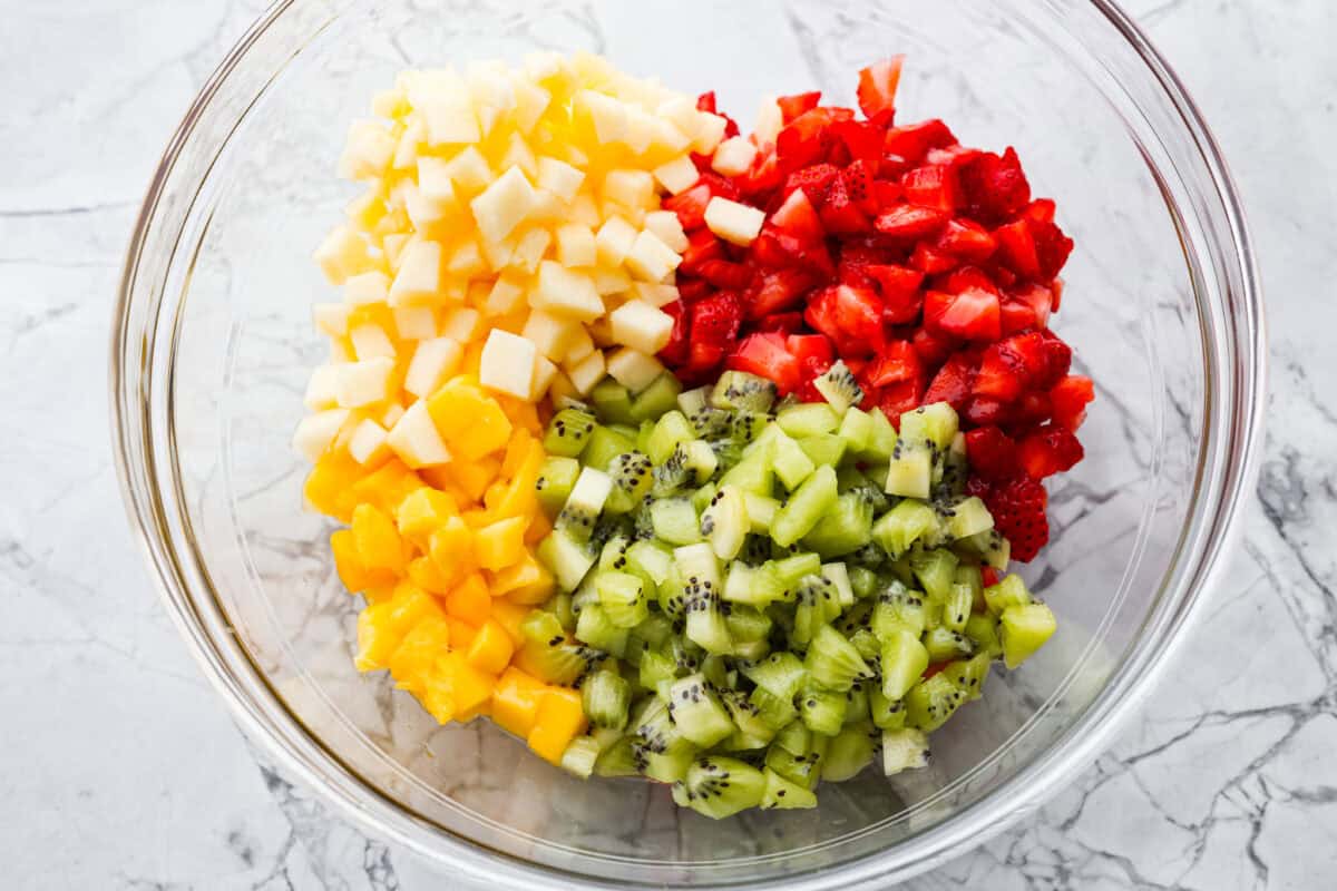 Vibrant fruit salsa is a fresh, juicy twist on your favorite snack! Sweet berries, tropical mango, and a splash of lime alwaysย steal the spotlight! Especially when served with crispyย cinnamon chips! Diced fruit added to a bowl.