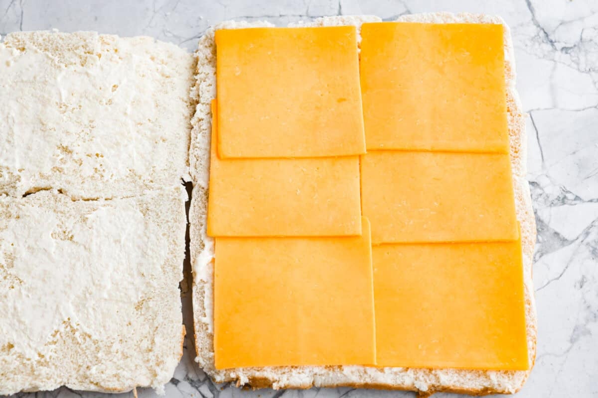Ham and cheese are a match made in heaven! Add sweet Hawaiian rolls, topped with an incredible glaze, and you've got something magical! These Ham and Cheese sliders are super easy and insanely delicious! A layer of cheese added to one half of the cut rolls.